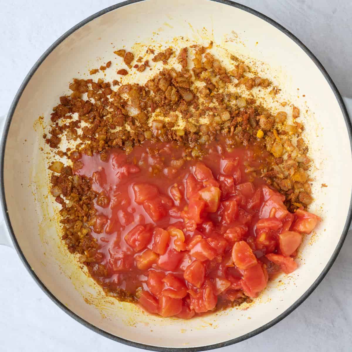 Cooked onions, garlic, ginger, and seasonings in a large skillet with the tomatoes added on top.