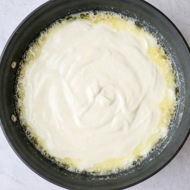 Yogurt added to sauteed garlic in a skillet.