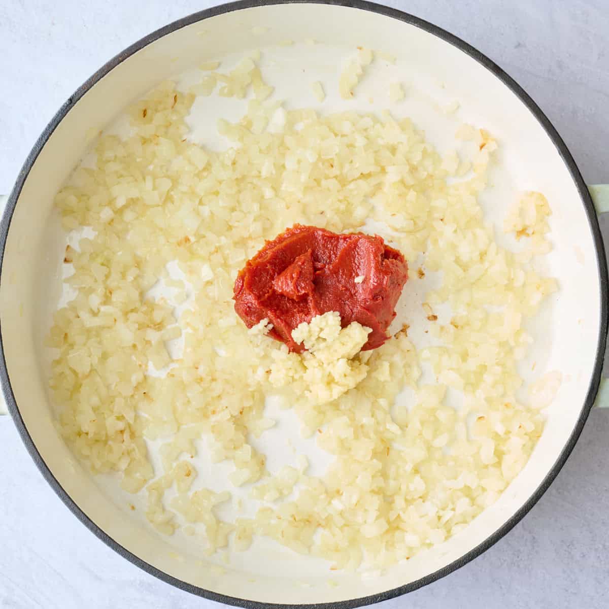 Onions after cooking until softened and lightly golden with garlic and tomato paste added before stirring.