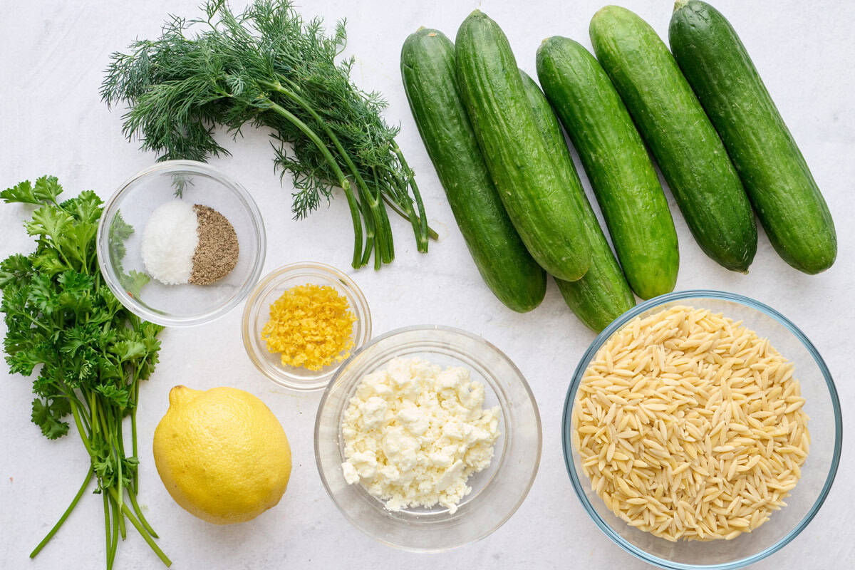 Ingredients for salad recipe: parsley, dill, salt and pepper, lemon, crumbled feta, cucumbers, and dry orzo.