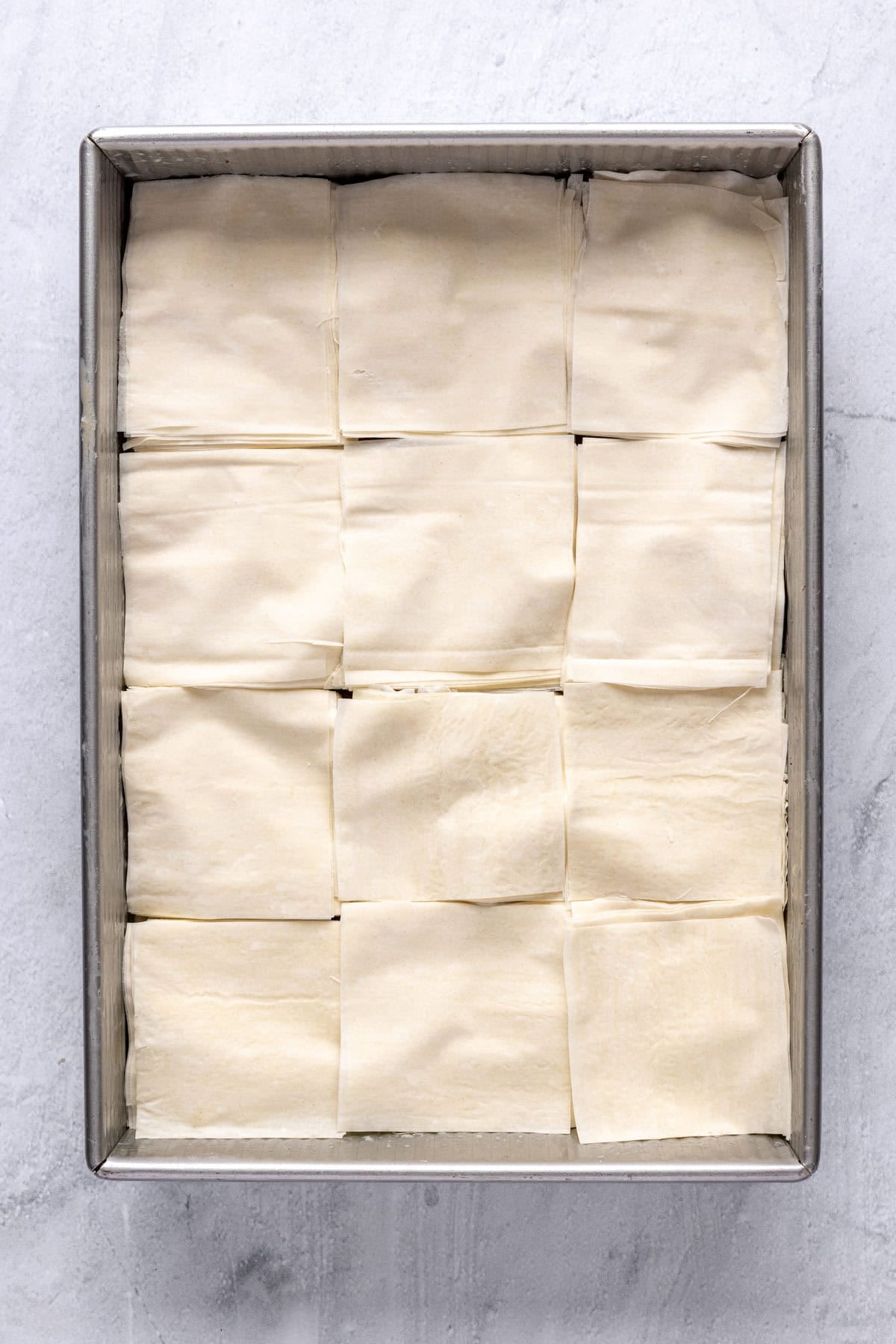 The remaining sheets of phyllo added on top of the spread beef mixture, and then cut into 12 squares.