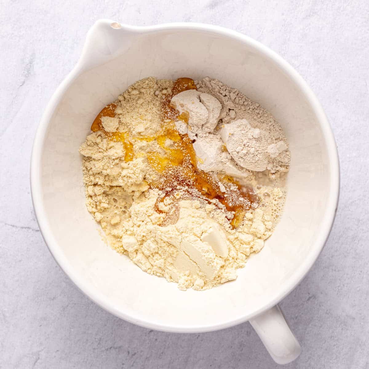 Almond flour, protein powder, oat flour, honey and water in a large bowl before mixing.