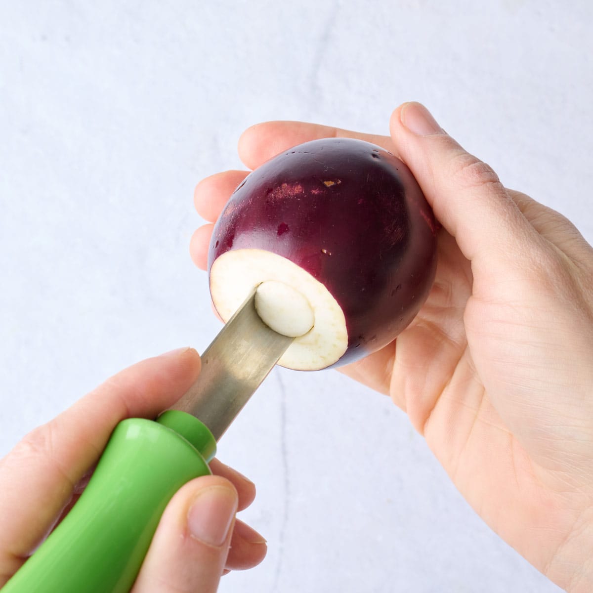 Coring an eggplant after cutting off top.