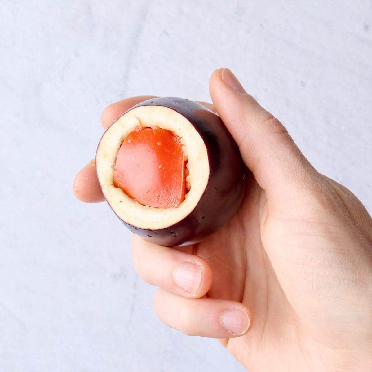 Chunk of tomato added over the beef and rice mixture stuffed into a baby eggplant.