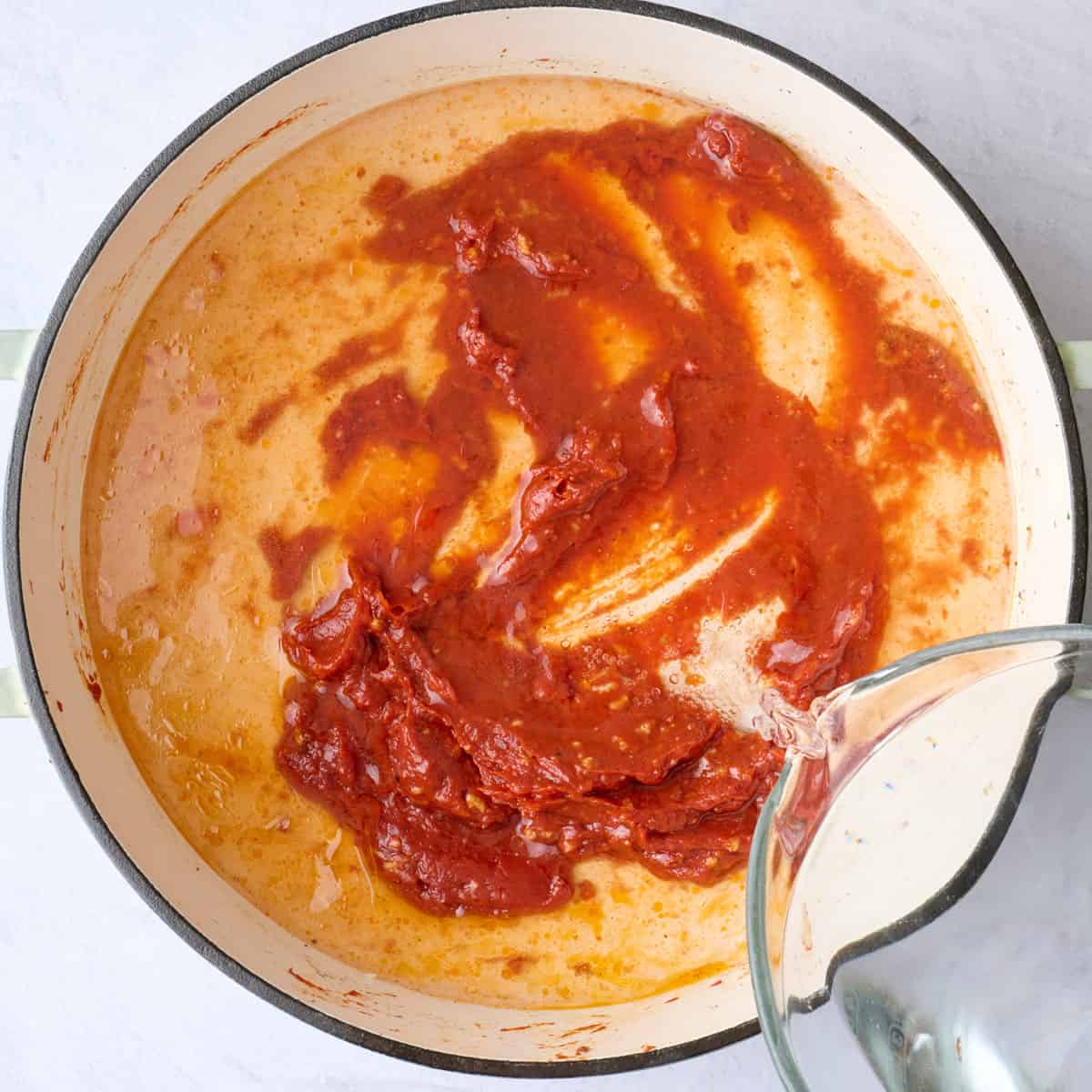 Water being poured into pot with tomato paste.