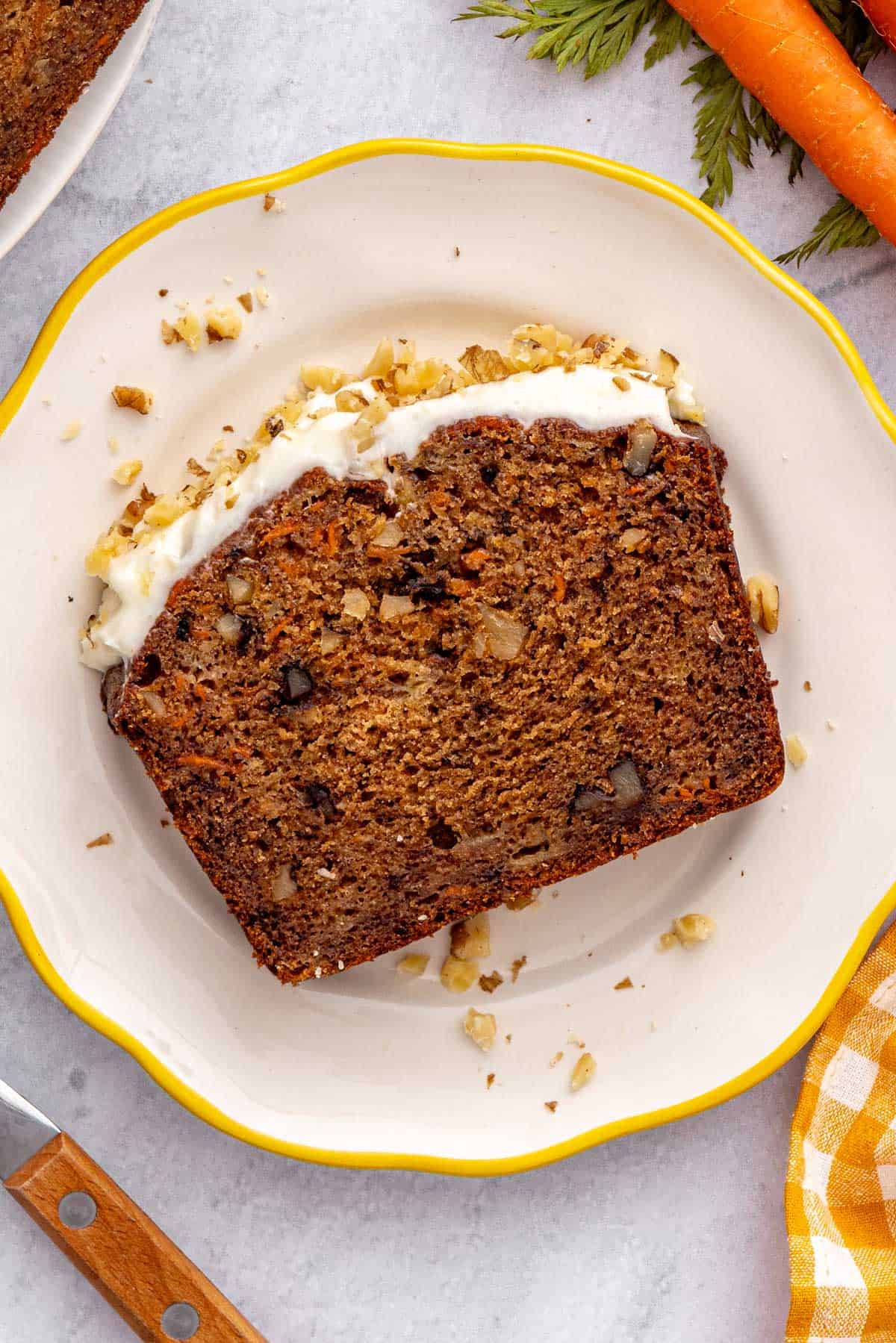 Slice of moist quick carrot banana bread recipe with walnuts and cream cheese frosting.