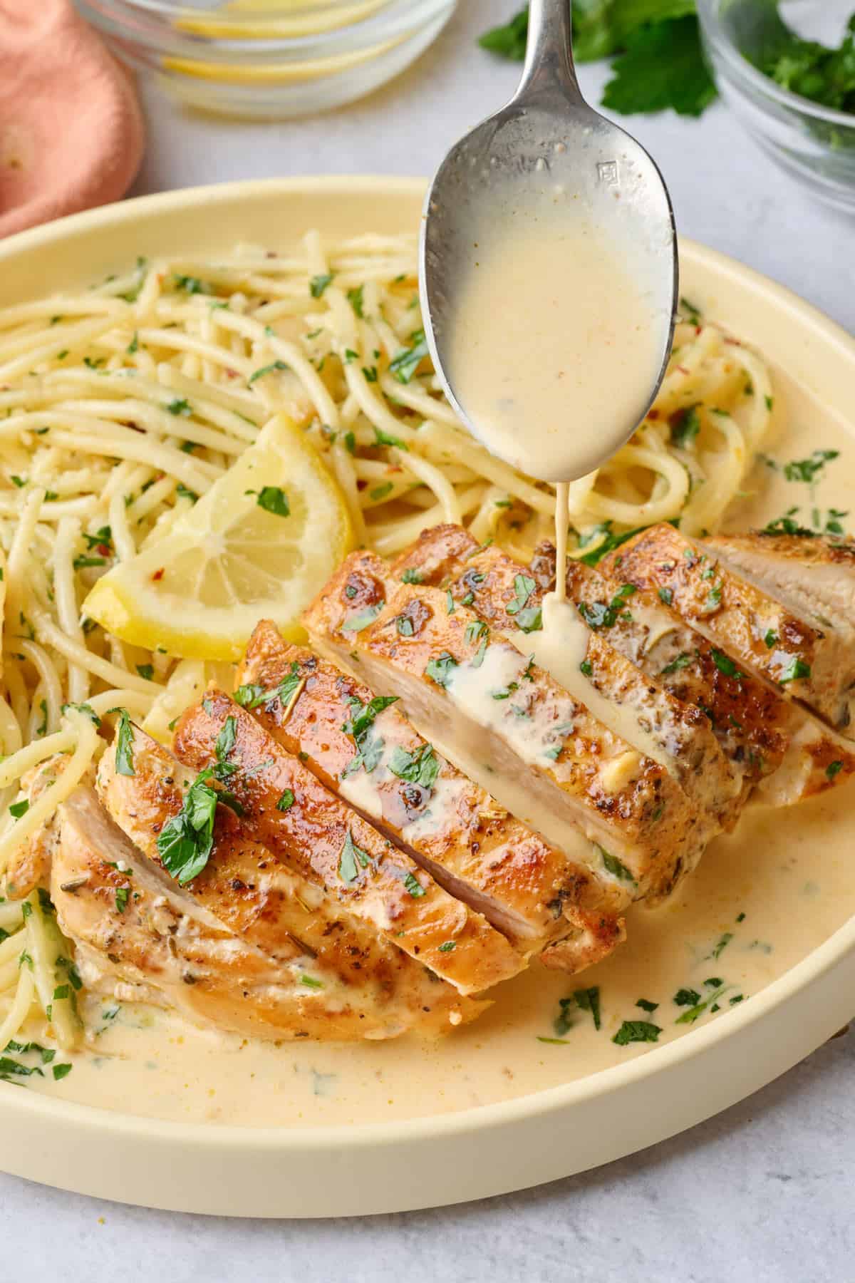 Serving of chicken served with Spaghetti Aglio e Olio chicken sliced, garnished with parsley and lemon.
