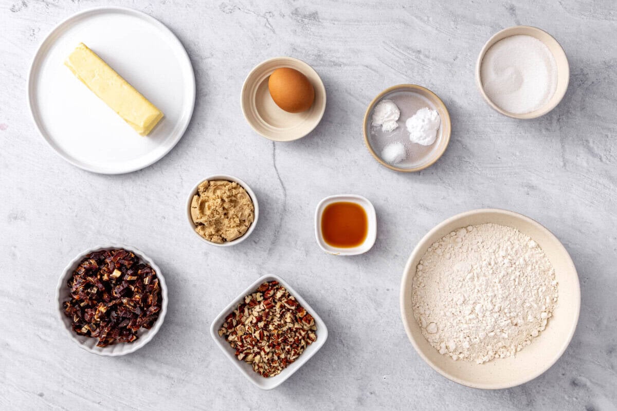 Ingredients for chewy cookies recipe: butter, chopped dates, brown sugar, chopped pecans, egg, vanilla, baking powder, baking soda, and salt, granulated sugar, and flour.