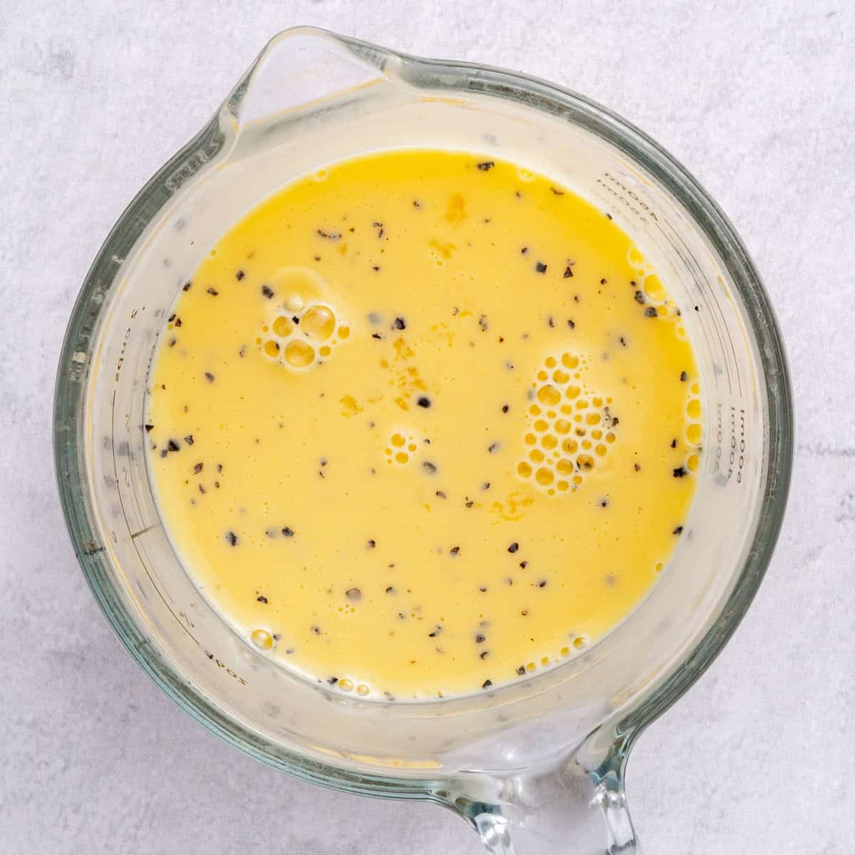 Eggs, milk and seasonings in a measure cup after whisking.