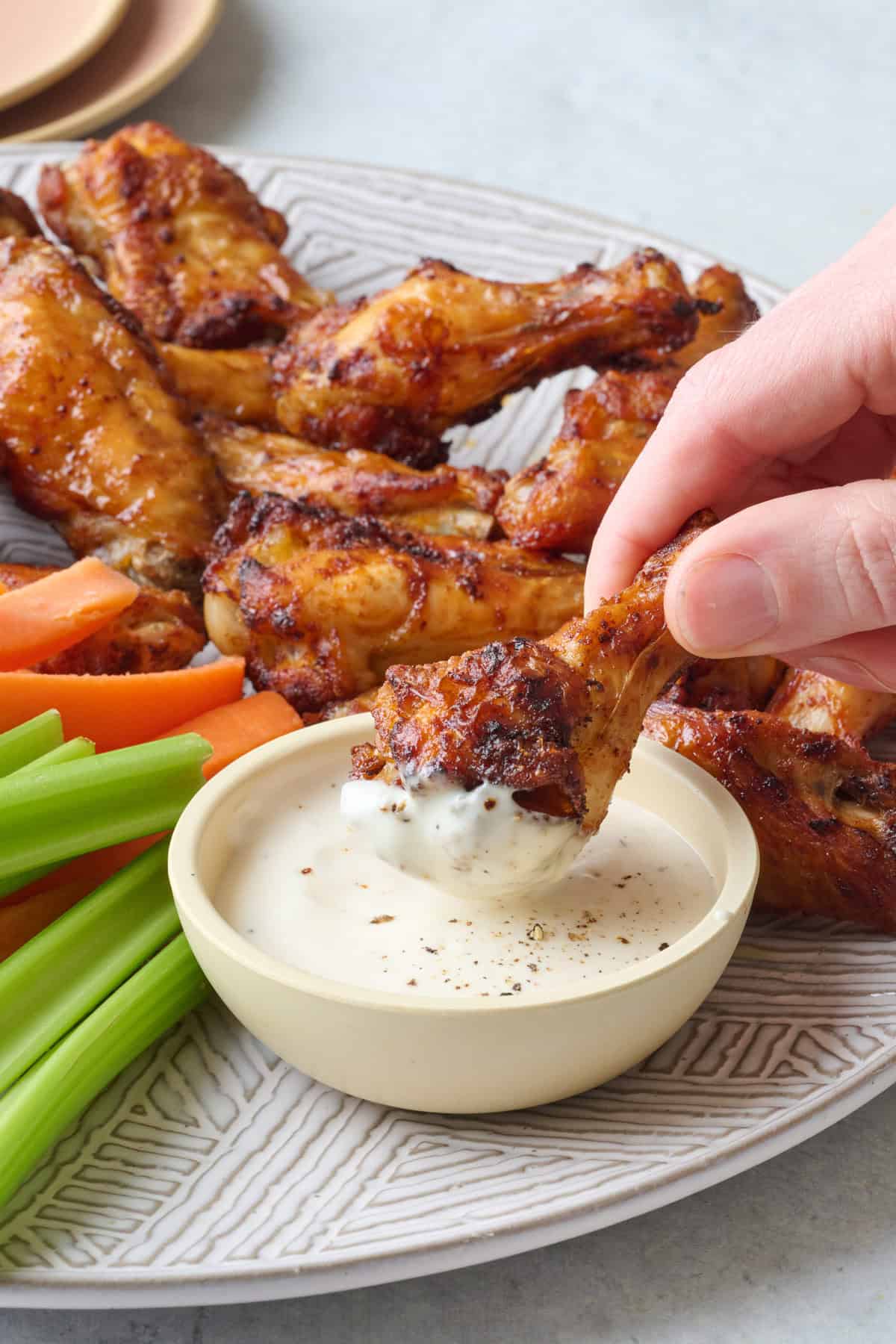 Crispy air fried chicken wing being dipped into ranch.
