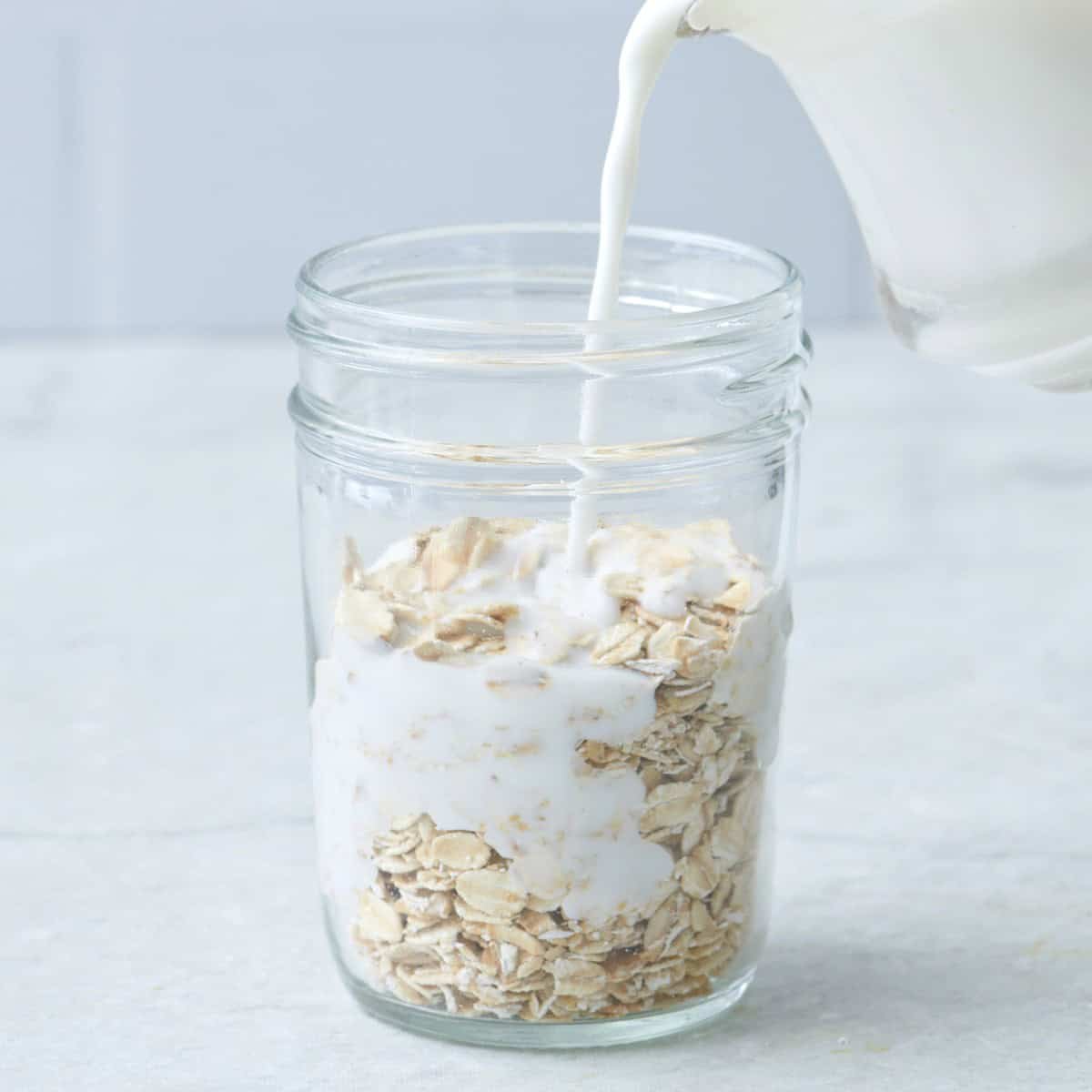 Pouring milk into a glass jar with milk.