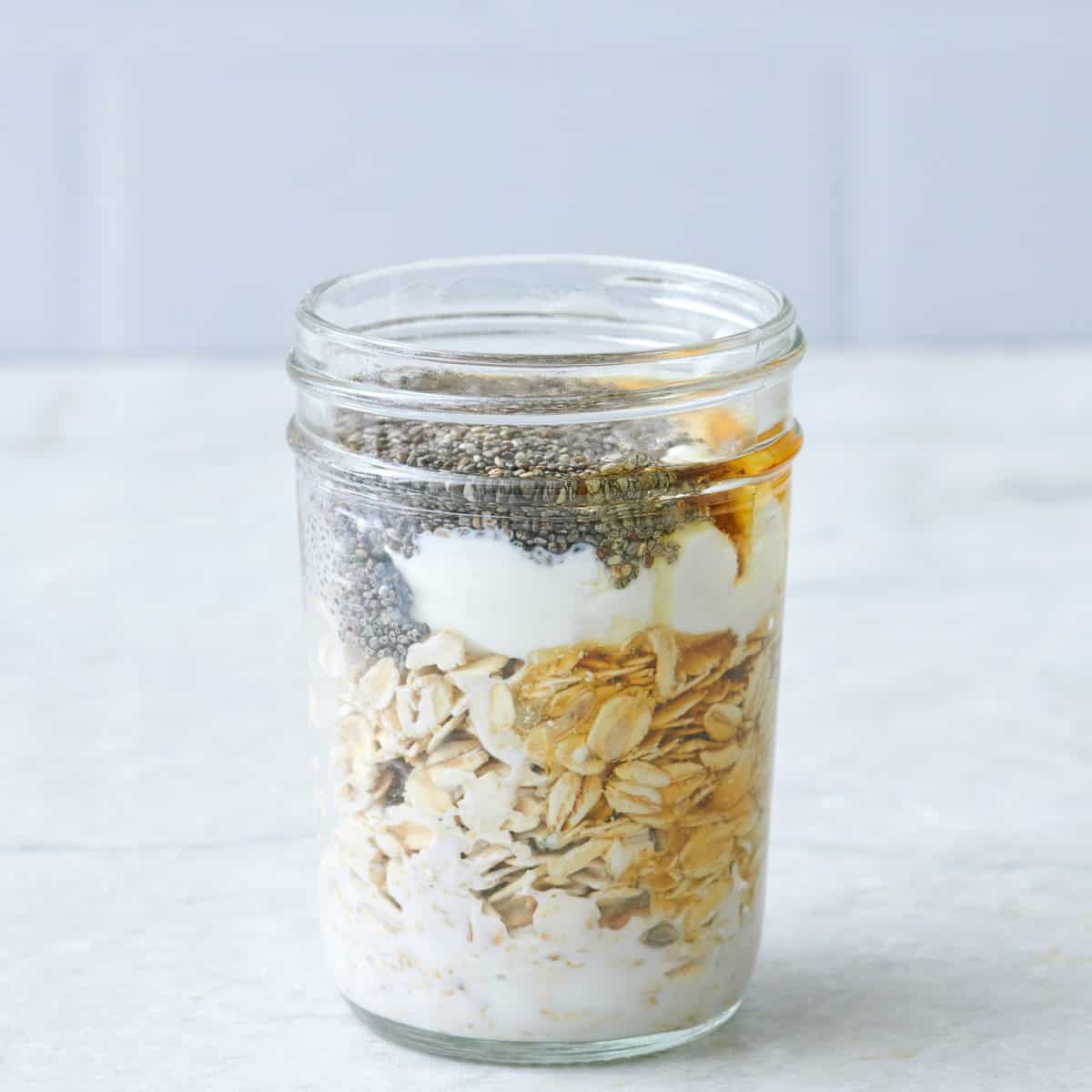 Chia seeds, honey and yogurt added to rolled oats in a glass jar before combininig.